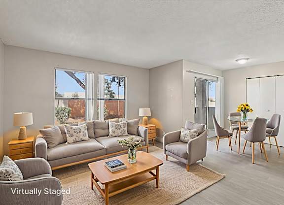 A living room with a grey couch, a wooden coffee table, and a dining table with chairs.