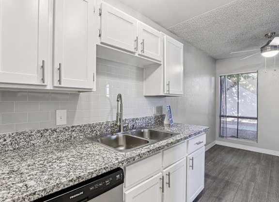 A kitchen with granite countertops and white cabinets.