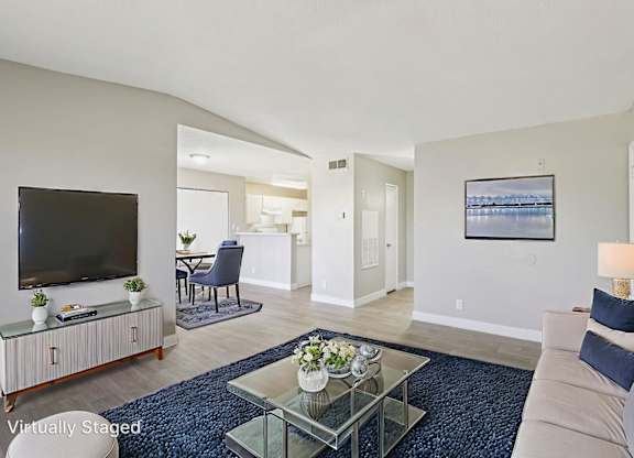 A living room with a television, a sofa, and a glass coffee table.