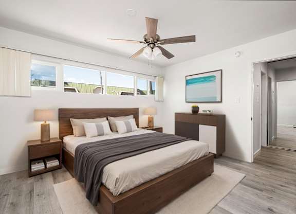 A bedroom with a bed, nightstand, and a ceiling fan.