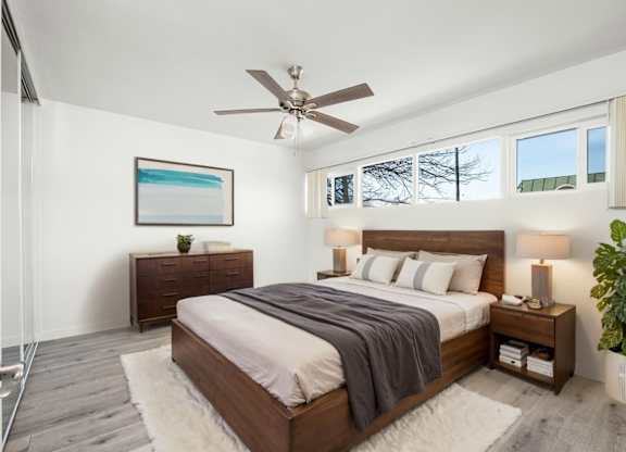 A bedroom with a large bed and a ceiling fan.