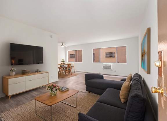 A living room with a black couch and a wooden coffee table.