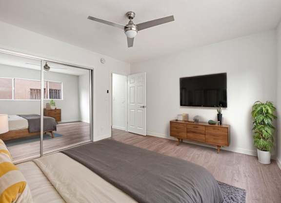 A bedroom with a bed, a ceiling fan, and a sliding glass door.