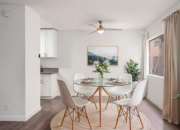 A dining room with a glass table and white chairs.