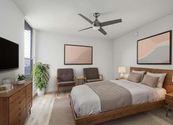 A bedroom with a large bed, a ceiling fan, and a painting on the wall.