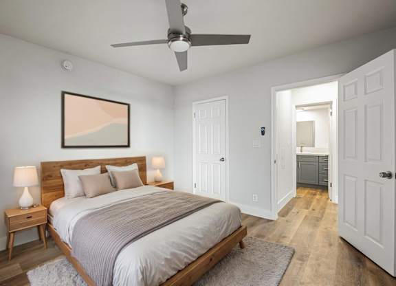 A bedroom with a bed, nightstands, and a ceiling fan.