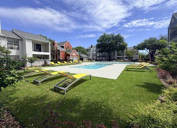 A swimming pool surrounded by a grassy area and benches.