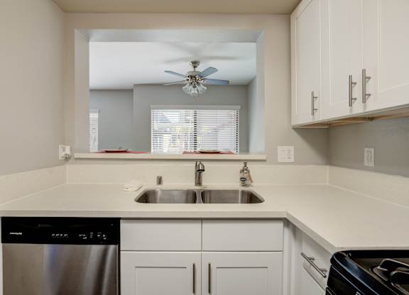 a kitchen with white cabinets and a sink and a ceiling fan