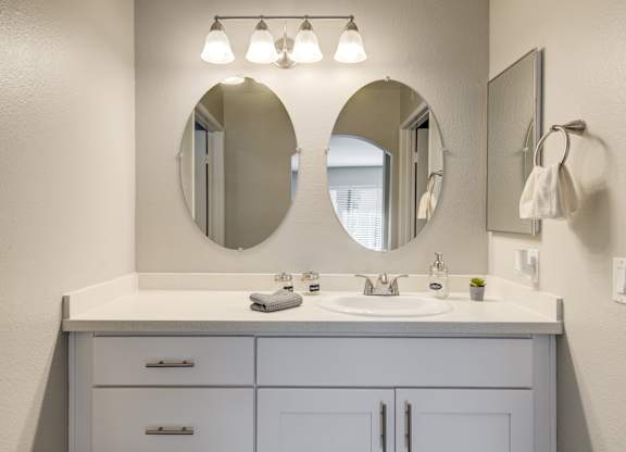 a white bathroom with two mirrors and a sink