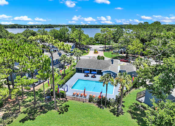 A bird's eye view of a house with a swimming pool surrounded by trees.