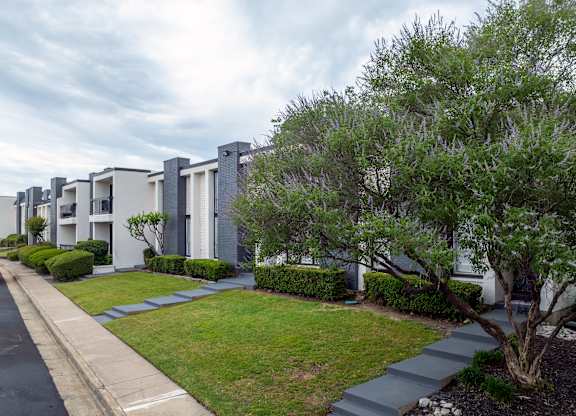 A row of modern houses with green trees in front.