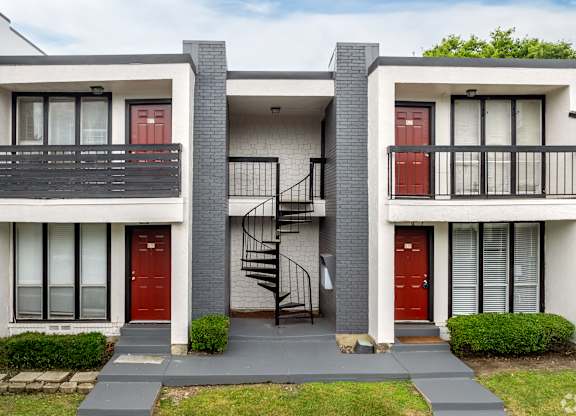 A modern two-story house with a red door and a black metal staircase.