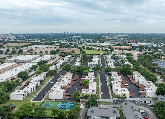 A view of a city from a high vantage point with buildings, roads, and a basketball court.