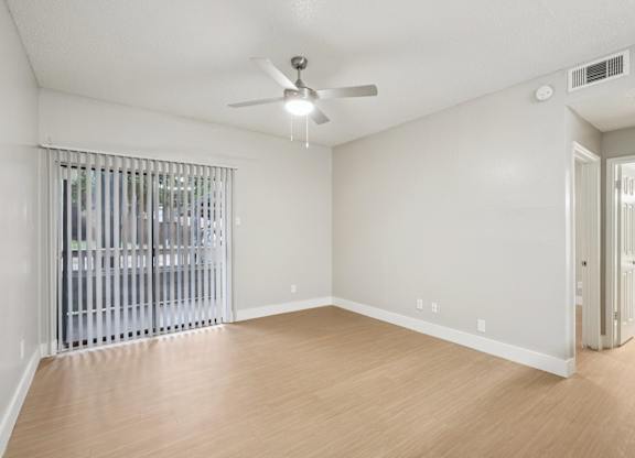 A room with a ceiling fan and a window with blinds.