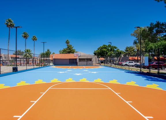A basketball court with a blue and orange surface and white lines.