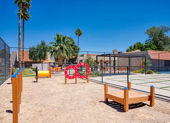 A playground with a wooden bench, a fence, and a swing set.