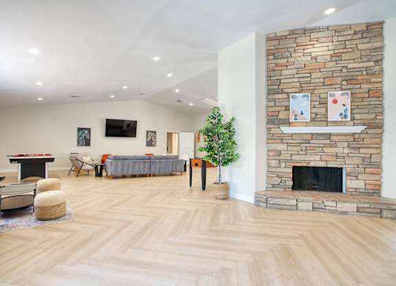 A living room with a stone fireplace and a television.