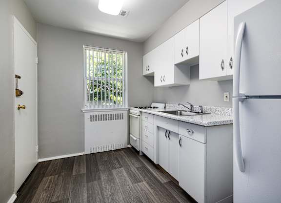 an empty kitchen with white cabinets and a window at Hampton Gardens, Missouri, 63139