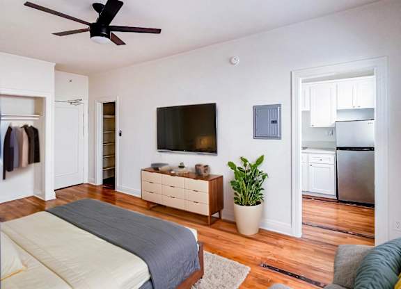 A bedroom with a bed, dresser, and a ceiling fan at Kenmore Park Apartments, Los Angeles, California