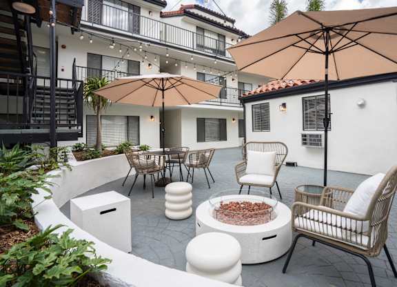 a patio with tables and chairs and umbrellas and a fire pit
