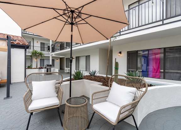 a patio with two chairs and an umbrella