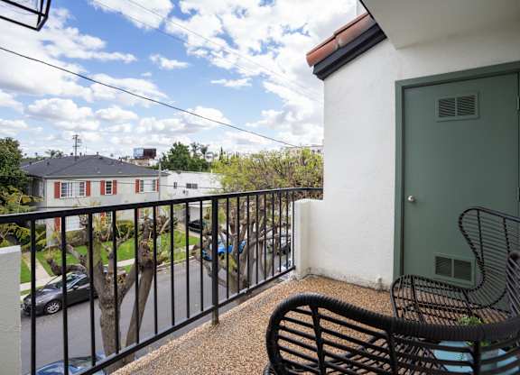 a balcony with a green door and two chairs on it