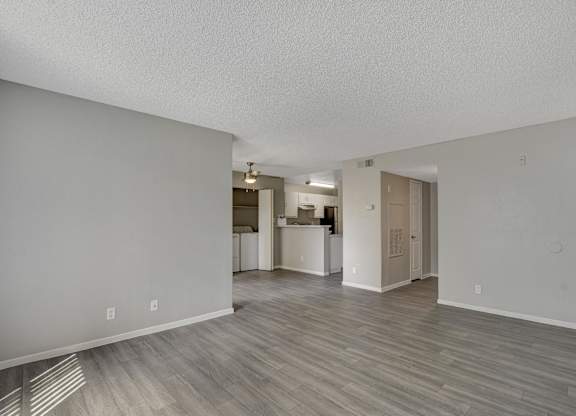 A room with a kitchen in the background and a hallway leading to a bathroom.
