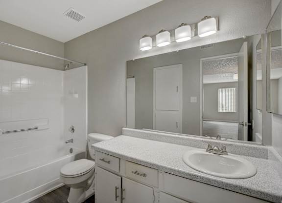 A white bathroom with a toilet, sink, and mirror.