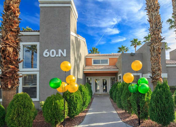 A building with the number 60 on it is surrounded by green bushes and palm trees.