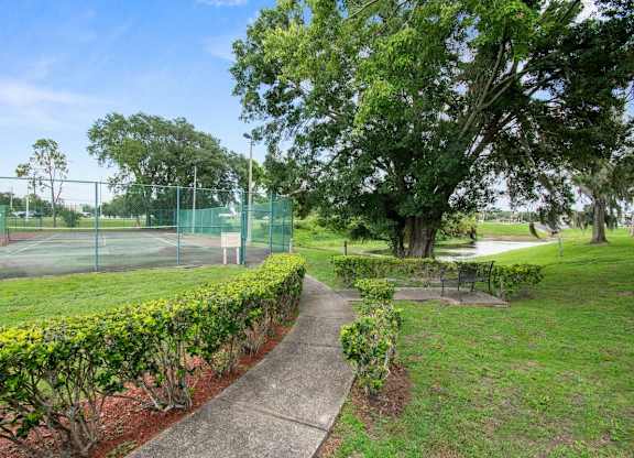 A green park with a fence and a tennis court.