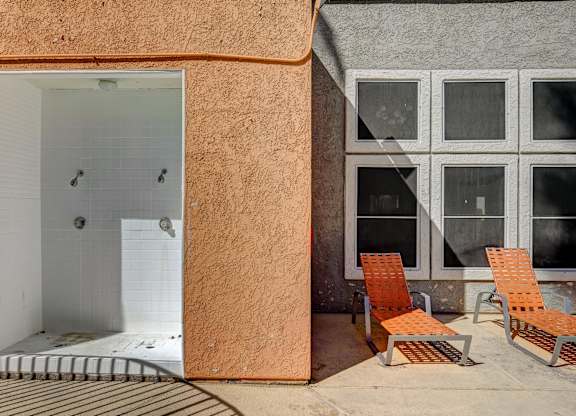 A bathroom with a walk-in shower and two chairs.
