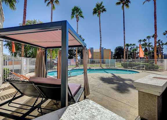 A patio with a pool and a chair under a canopy.