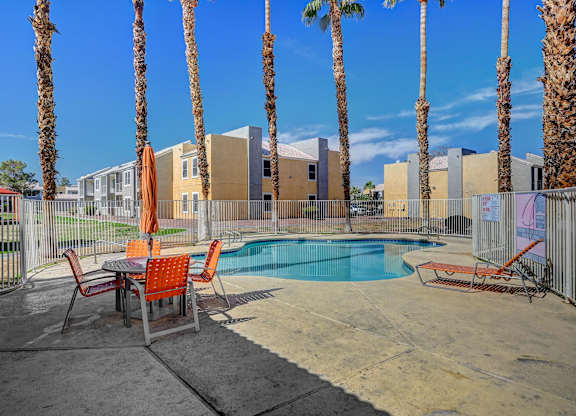 A pool surrounded by palm trees and chairs.