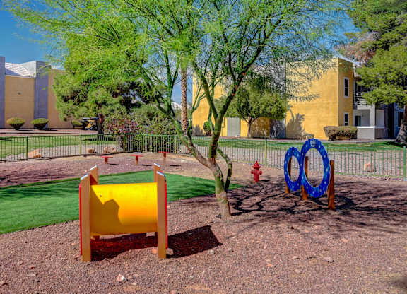 A playground with a yellow slide and a blue and red ring structure.