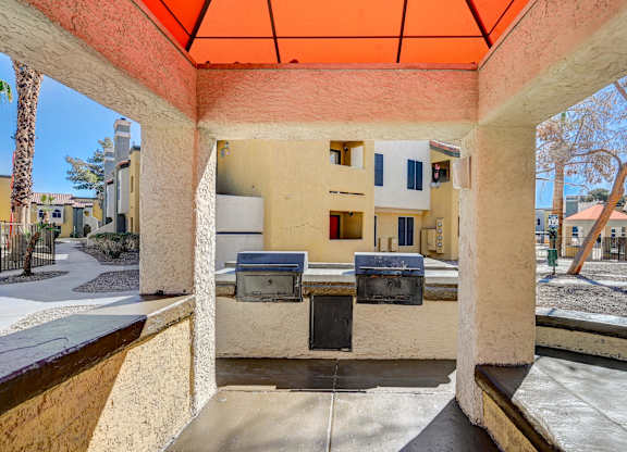 A patio with a table and chairs under an orange awning.