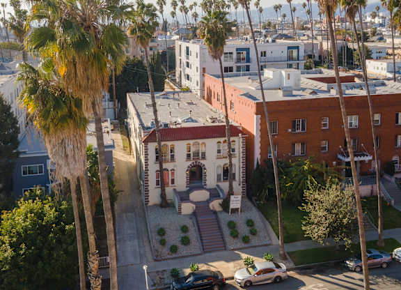 A building with a red roof is surrounded by palm trees at Hillstone Flats Apartments, Los Angeles, CA