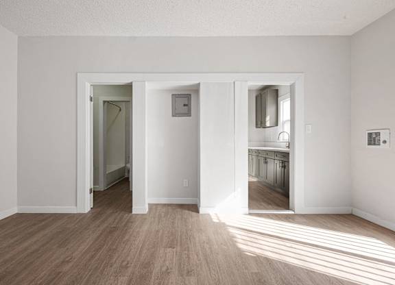 A room with white walls and wooden flooring with three open doors at Hillstone Flats Apartments, California