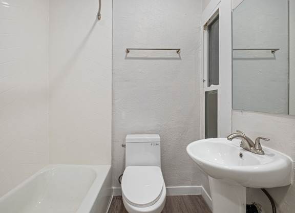 A white toilet sits next to a white sink in a small bathroom at Hillstone Flats Apartments, California 90004