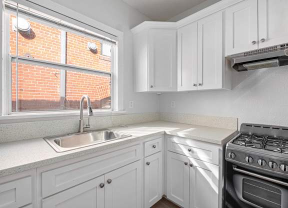 A kitchen with white cabinets and a stove top oven at Hillstone Flats Apartments, Los Angeles, California