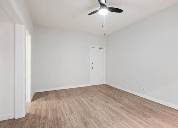 A room with a ceiling fan and light fixture, a door, and a wooden floor at Hillstone Flats Apartments, Los Angeles, CA, 90004