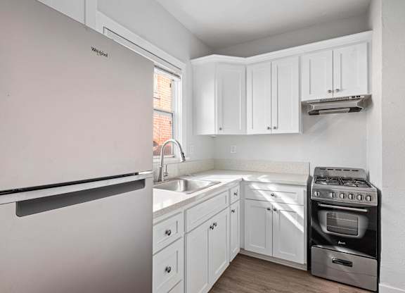A kitchen with a white fridge and a stove top oven at Hillstone Flats Apartments, Los Angeles