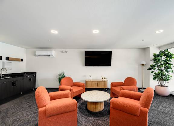 A room with orange chairs and a white table.