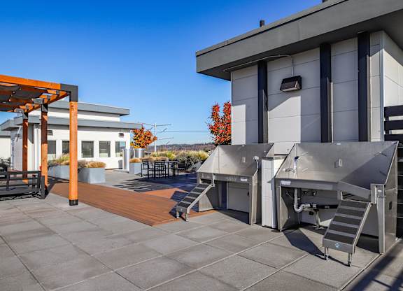 A modern building with a grey and white exterior and a wooden pergola.