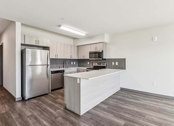 A modern kitchen with a refrigerator, microwave, and oven.