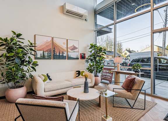 A living room with a couch, chair, and potted plant.