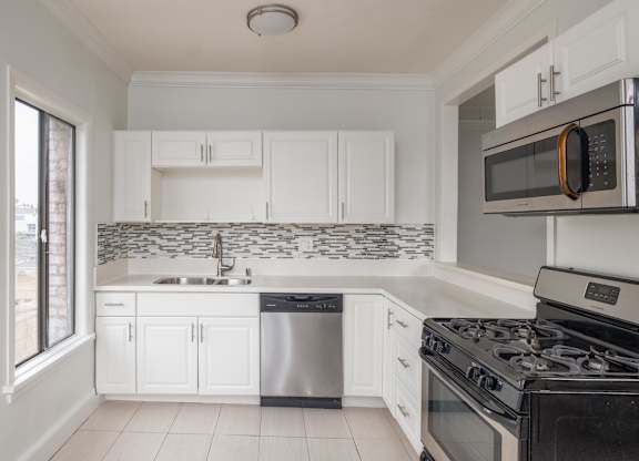 A kitchen with white cabinets and a black stove top oven at Mariposa Willows Apartments, Los Angeles, CA