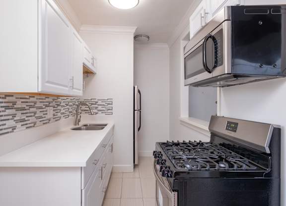 A kitchen with a black stove and white cabinets at Mariposa Willows Apartments, Los Angeles, California