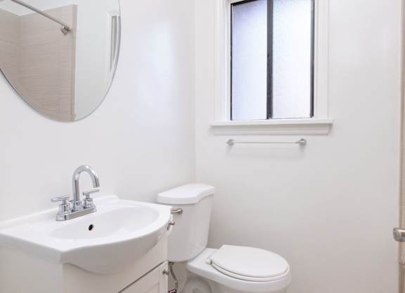 A white toilet sits next to a sink in a bathroom at Mariposa Willows Apartments, Los Angeles