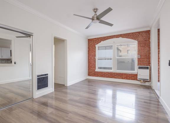 A room with a ceiling fan and a brick wall at Mariposa Willows Apartments, Los Angeles, 90004