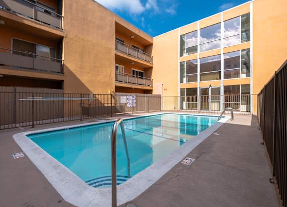 A small pool in a courtyard surrounded by buildings at Menlo Terrace Apartments, California 90006